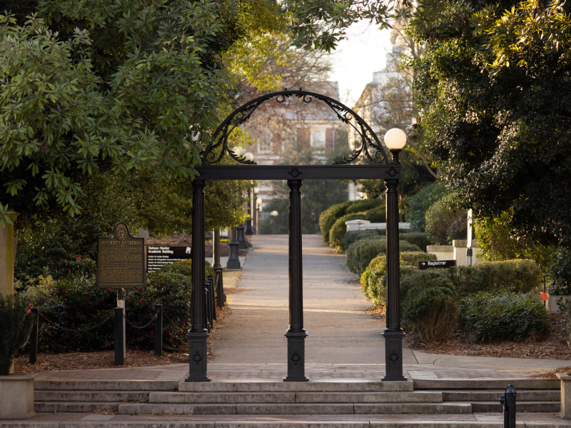 The Arch is highlighted by early morning sunlight with the UGA Historic Marker and North Campus in the background.